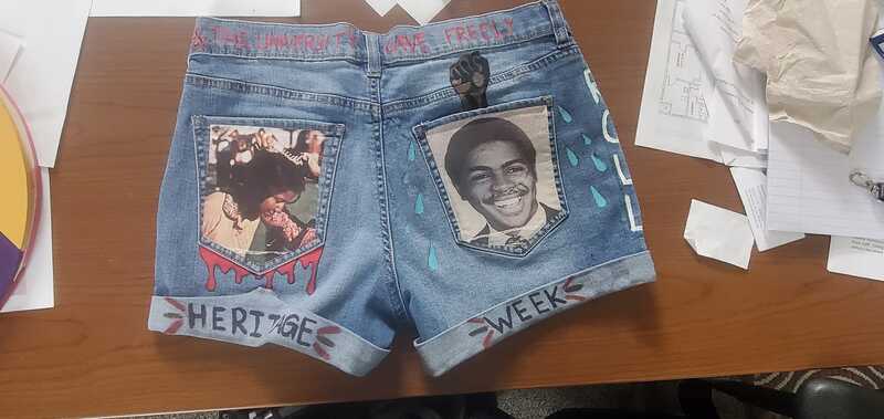 Distressed pair of jean shorts with two yearbook photos on the pockets and handwritten text on the hem.