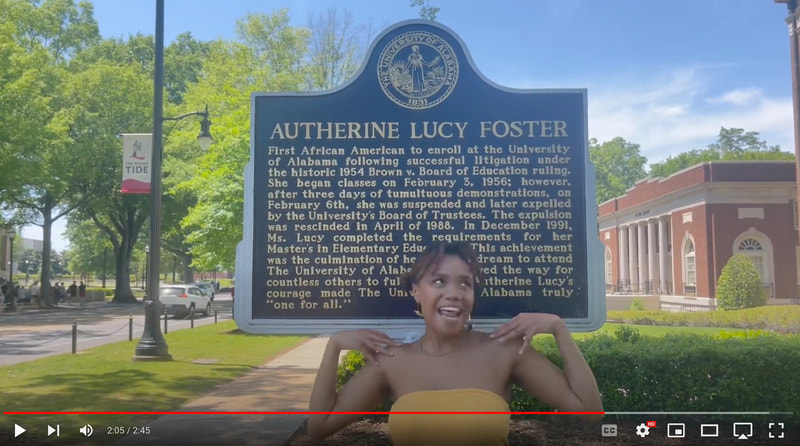 Black woman dancing in front of the Autherine Lucy Foster historical marker. 